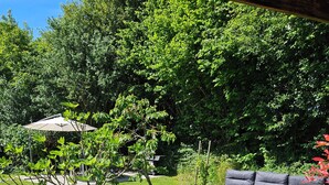 Un patio trasero con césped, un hogar para fogata, un banco de madera y una pérgola.