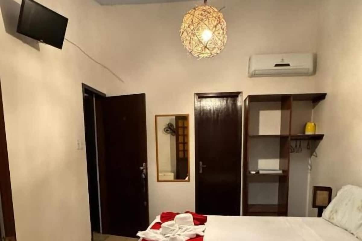Une chambre d’hôtel avec un lit, un luminaire suspendu, une armoire et un miroir.