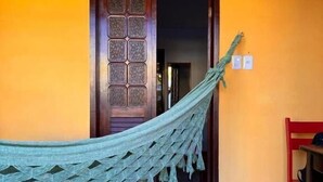 A hammock tied to a door frame in a room with a tiled floor and a yellow wall. - Pousada Flor de Porto (Ipojuca)