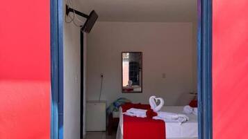 Una habitación con cama, un escritorio pequeño y un espejo en la pared.