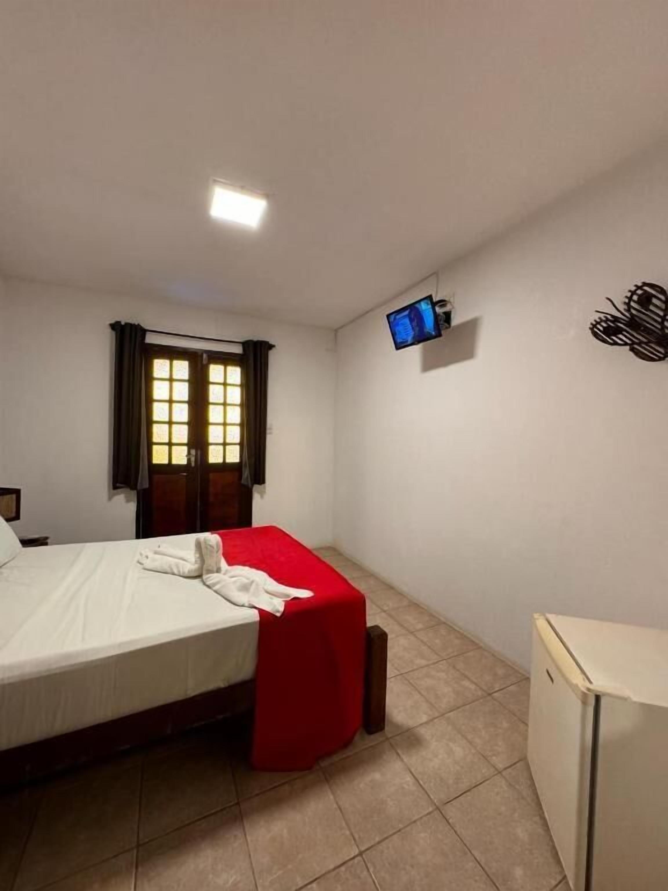 A small, clean room with a bed, a TV mounted on the wall, and a desk.