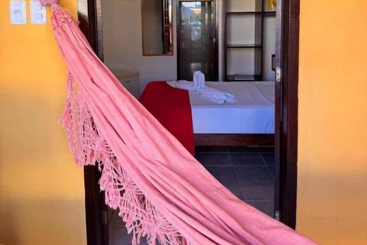 Une porte qui mène à une pièce où se trouvent un lit, une couverture rouge et une serviette blanche.