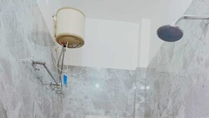 Un baño con inodoro, ducha y pared de mármol.