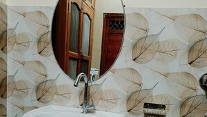 Un baño con un lavabo blanco, un espejo redondo y un papel tapiz estampado.