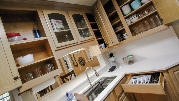 Una cocina con armarios de madera, un lavamanos y diversos utensilios de cocina.