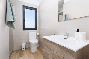 A modern bathroom with a shower, toilet, and sink.