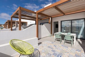 A modern outdoor patio with a dining table, chairs, and a green chair.