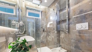 Une salle de bain moderne avec une douche à parois de verre, un lavabo blanc et un bidet.