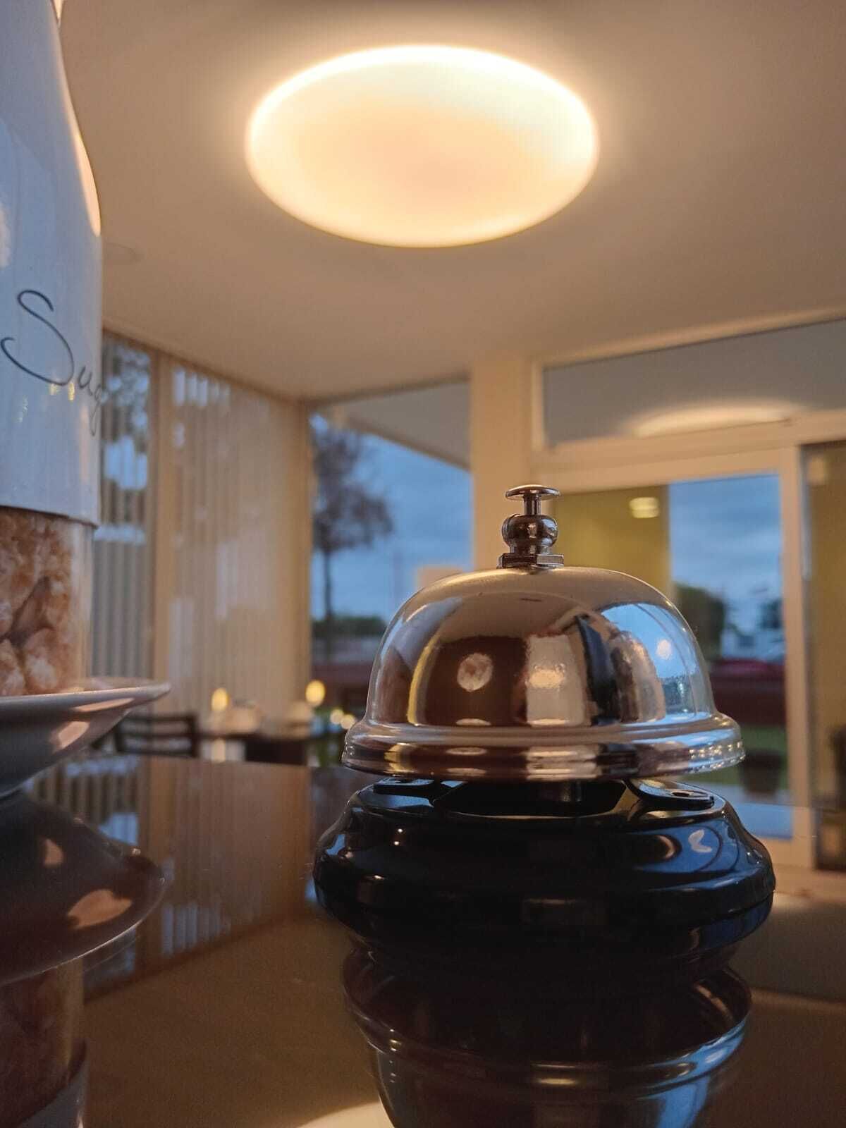 A coffee machine on a counter with a reflective surface, a glass container, and a sign with the word "Sugar".