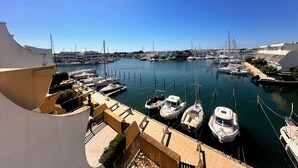 Un port de plaisance où sont amarrés de nombreux bateaux, un ciel dégagé et des bâtiments en arrière-plan.