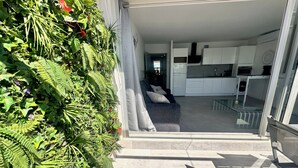 Un appartement moderne comprenant un espace de vie, une cuisine et un balcon agrémenté d’un mur végétal.
