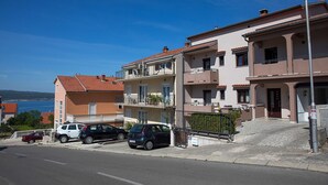 A multi-story residential building with balconies, a paved driveway, and a clear view of the sea. - Charming studio with sea view, bikes, baby crib, barbecue (Crikvenica)