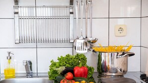 A kitchen with a sink, a pot of spaghetti, fresh vegetables, and a bottle of olive oil. - Charming studio with sea view, bikes, baby crib, barbecue (Crikvenica)