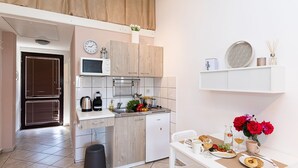 A compact kitchen with a microwave, kettle, and sink, a dining area with a table set for two, and a small refrigerator. - Charming studio with sea view, bikes, baby crib, barbecue (Crikvenica)