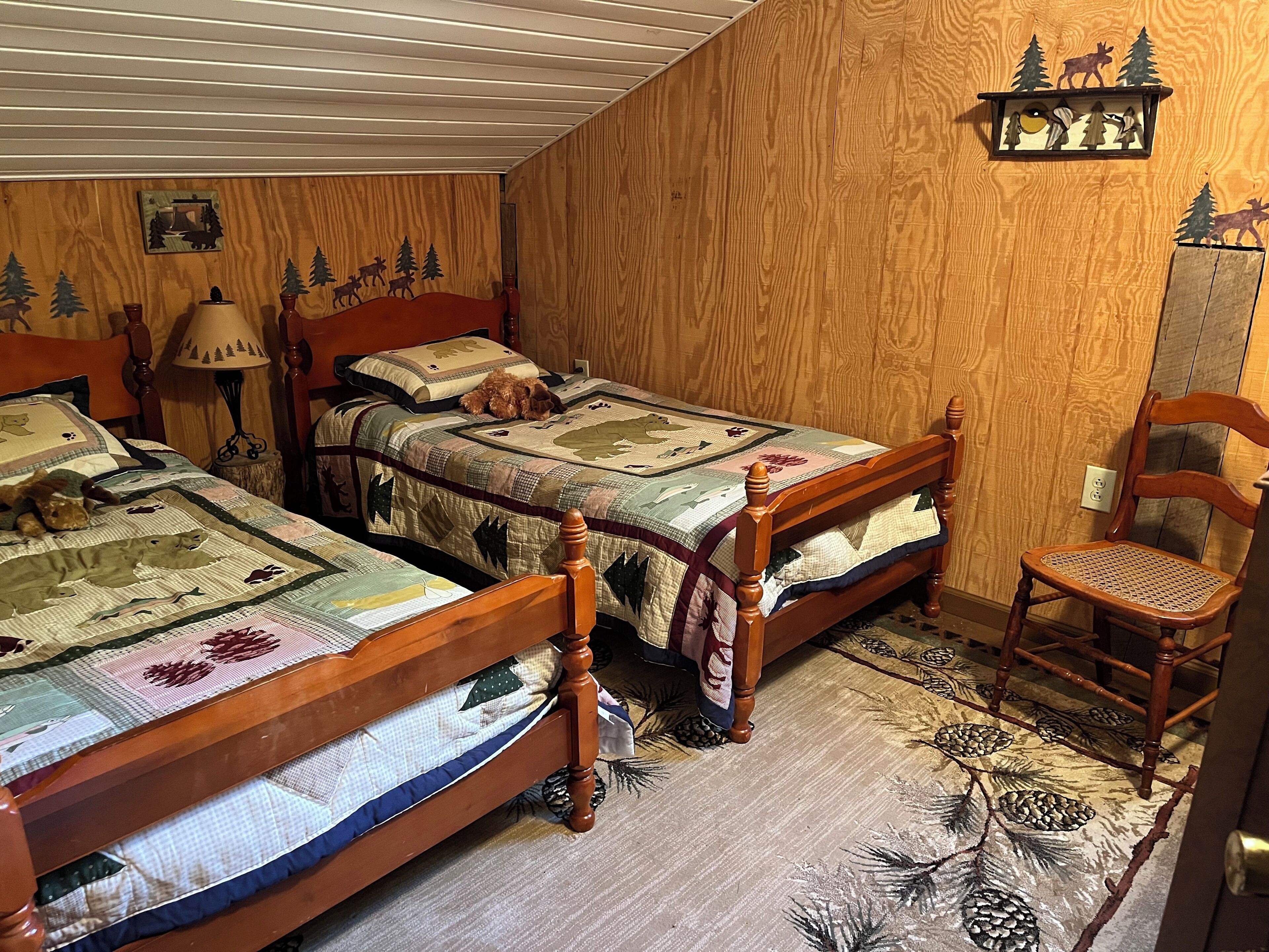 Een slaapkamer met twee houten bedden, een stoel en een muur versierd met bosdecoraties.