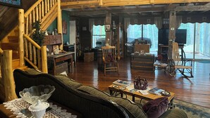 Un salon spacieux avec un escalier en bois, une cheminée accueillante et une grande fenêtre donnant sur l’extérieur.