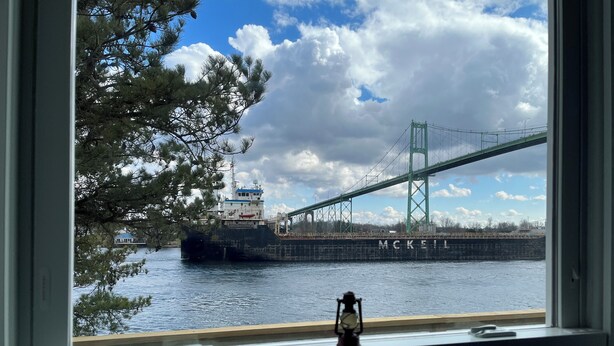 Une vue sur un pont et un navire nommé « McKeil », prise depuis une fenêtre avec une rambarde.