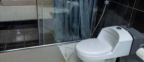 A modern bathroom with a white toilet, a glass shower enclosure, and a bathtub.