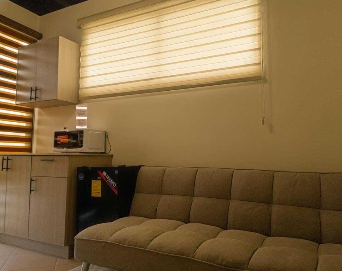 Un espace de vie compact comprenant un canapé, un four à micro-ondes et un réfrigérateur.