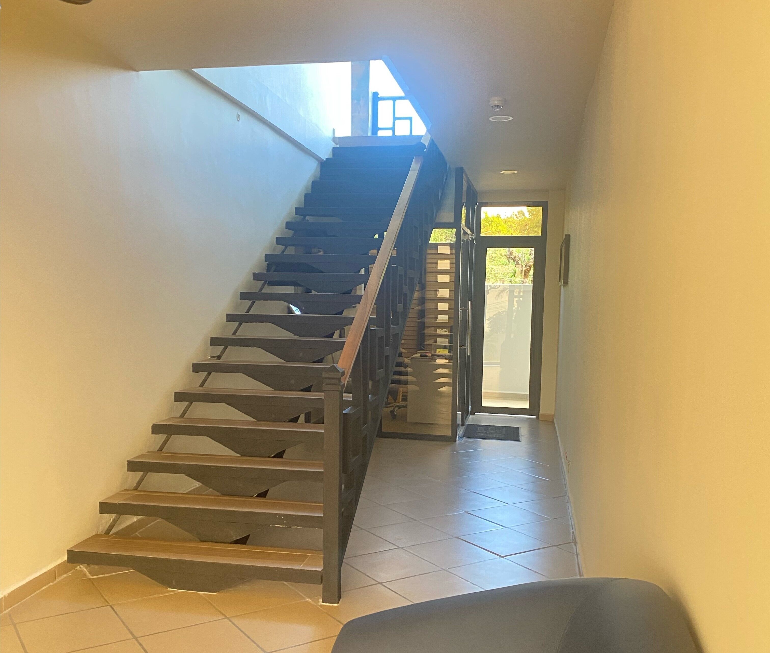 Una escalera que lleva a un rellano con una puerta al exterior.