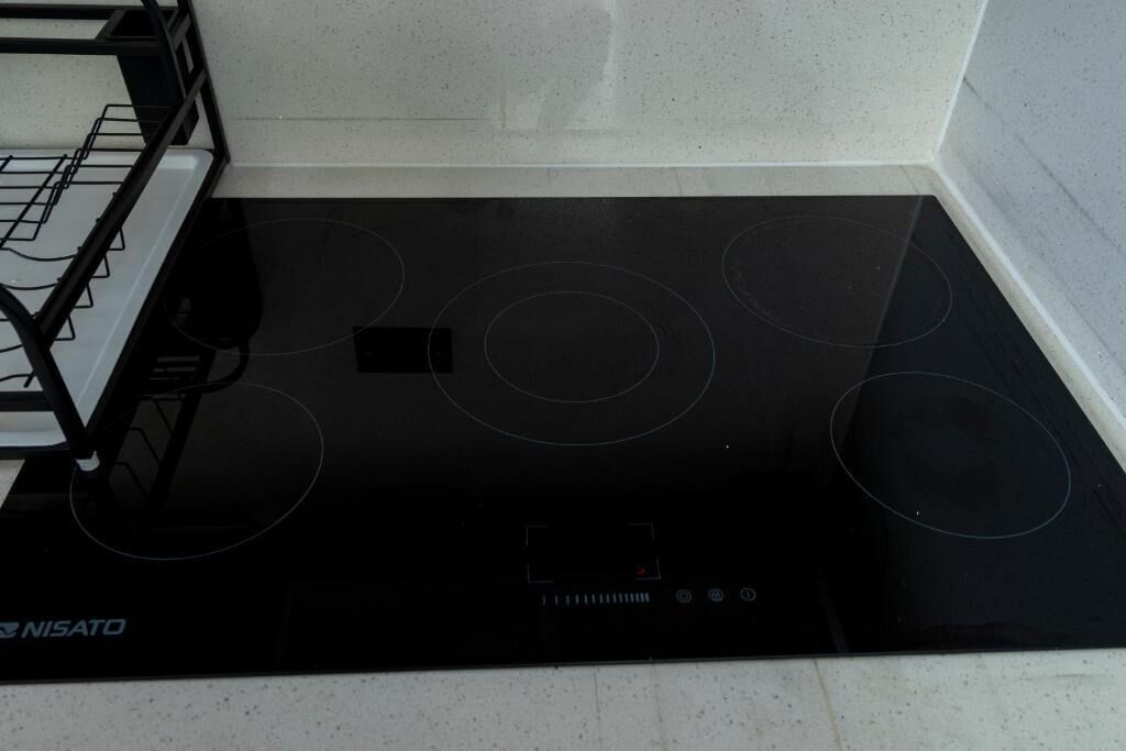 A black induction cooktop with four burners and a control panel.
