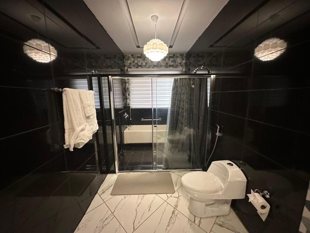 A modern bathroom with a glass shower enclosure, a toilet, and a bathtub.