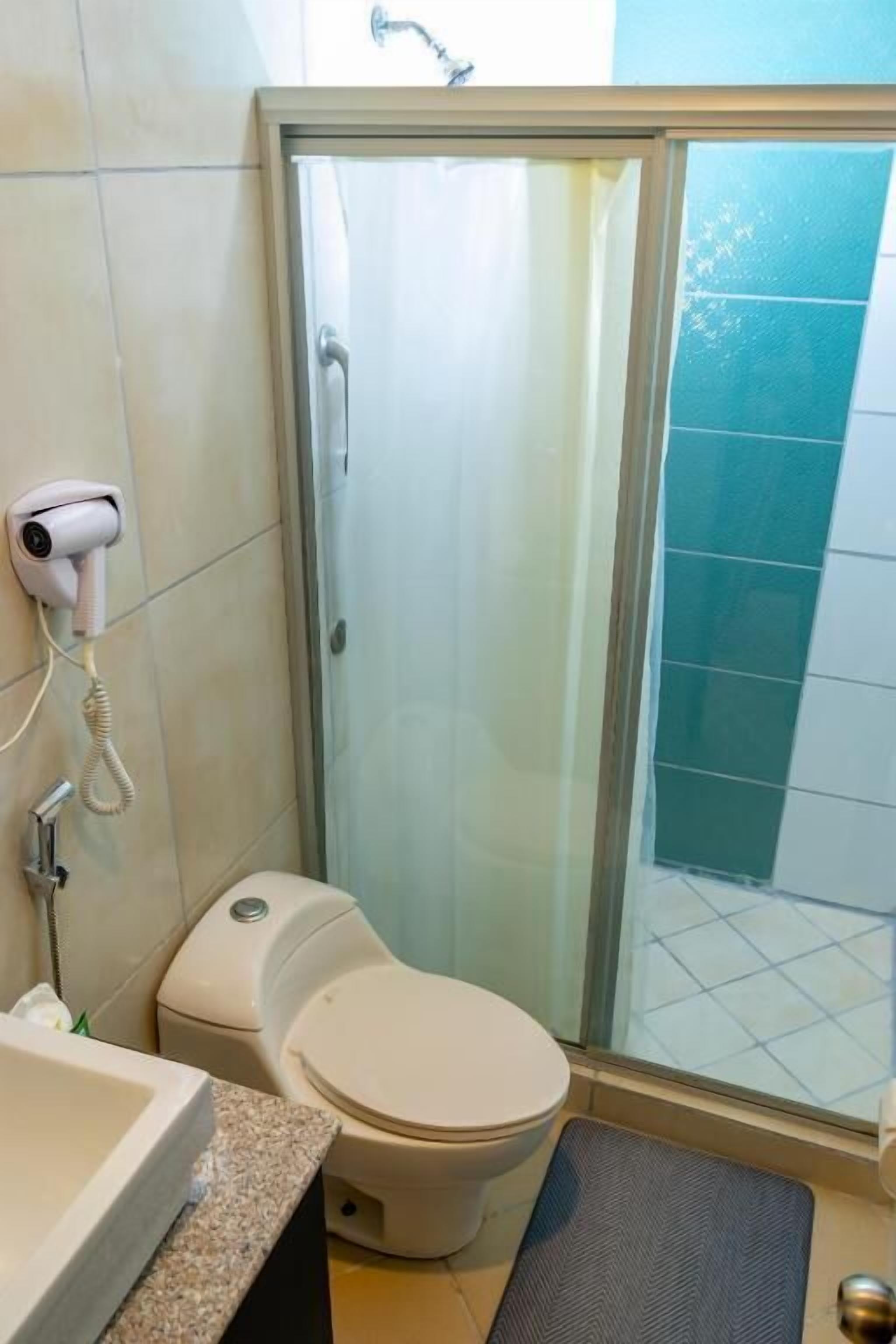 Ein Badezimmer mit Toilette, Duschkabine, Fön und Waschbecken.