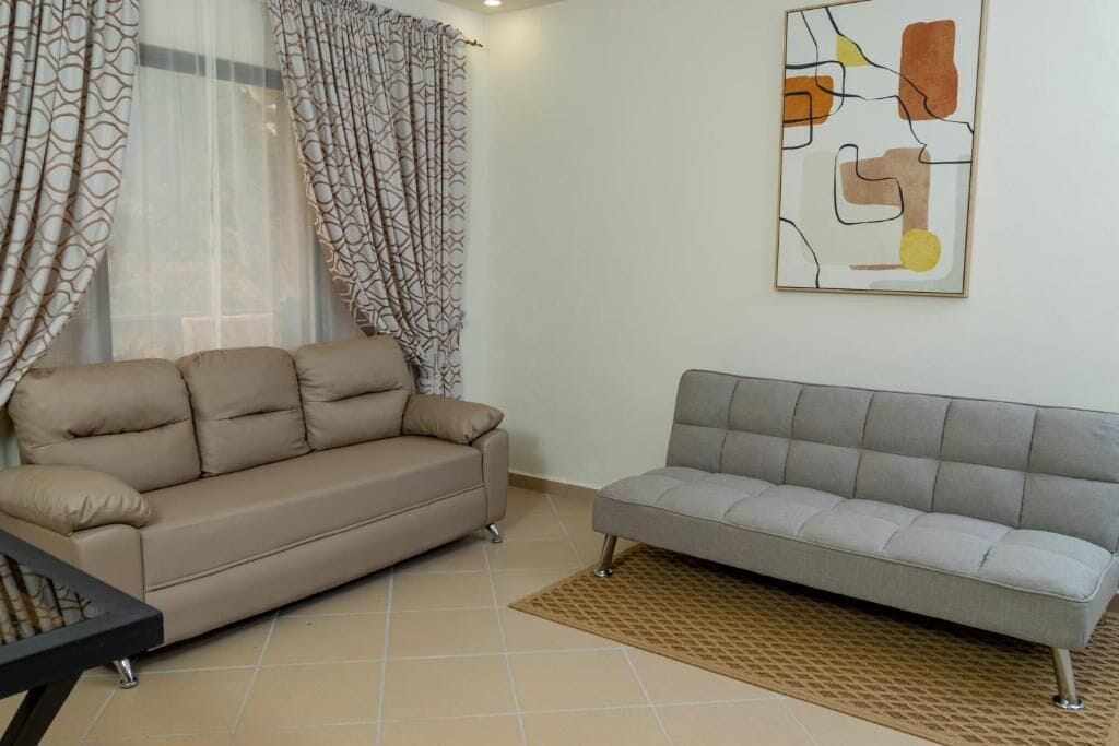 A living room with two sofas, a patterned curtain, and a wall art piece.