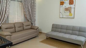 A living room with two sofas, a patterned curtain, and a wall art piece.