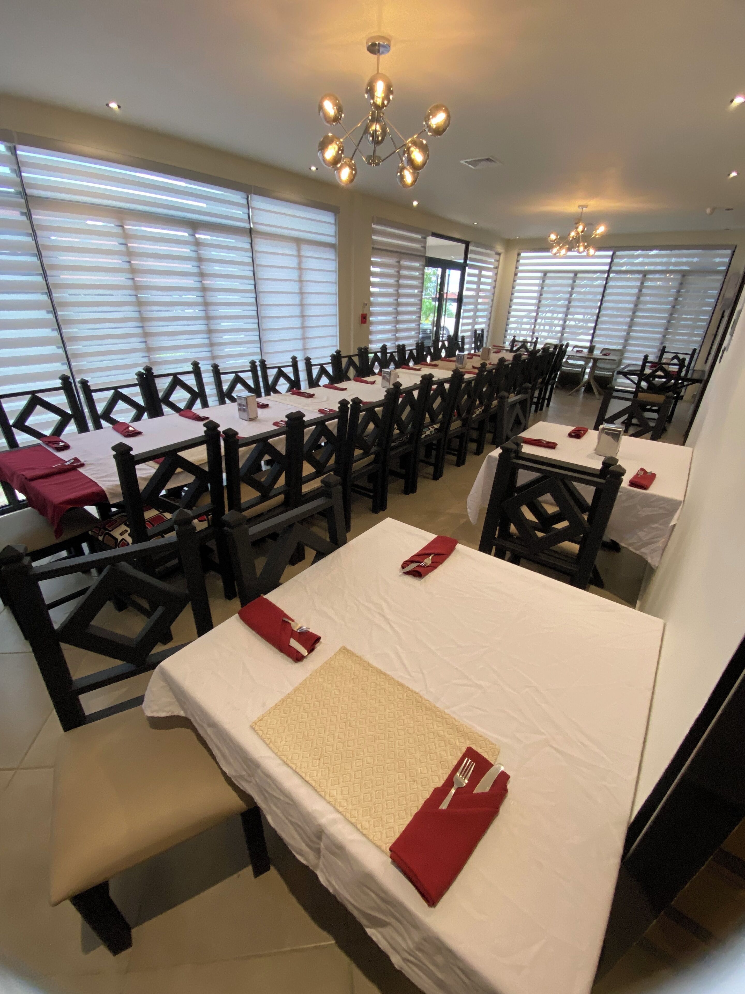 A conference room with long tables, black chairs, and white tablecloths.