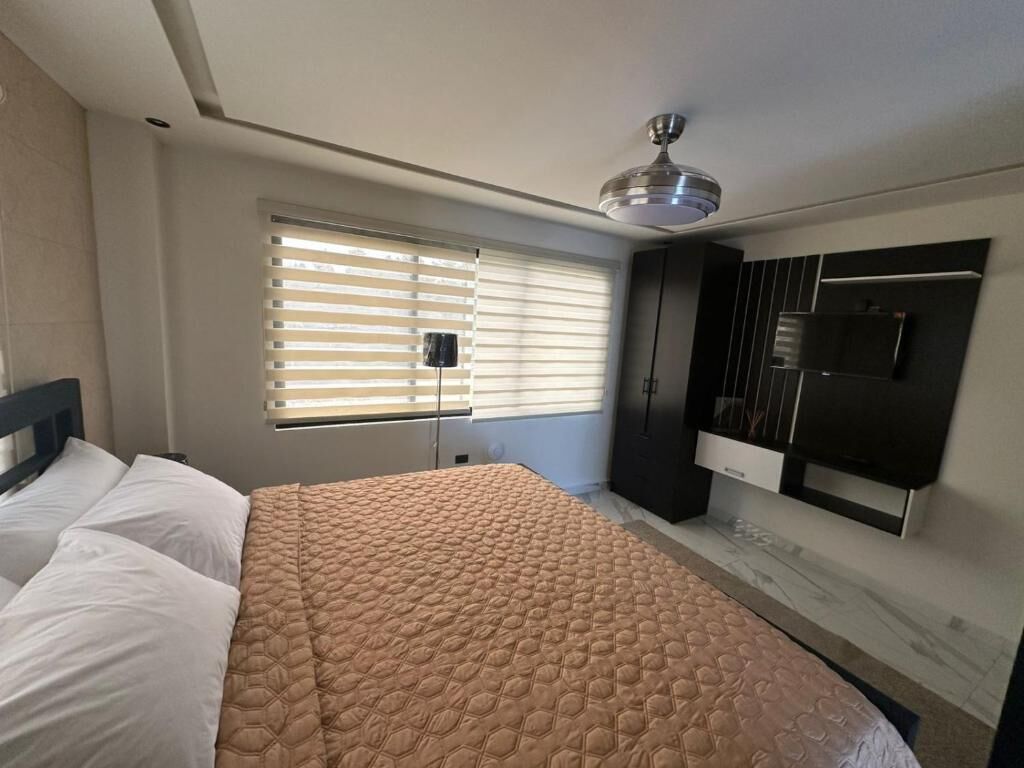 A bedroom with a bed, a wardrobe, a ceiling fan, and a window with blinds.