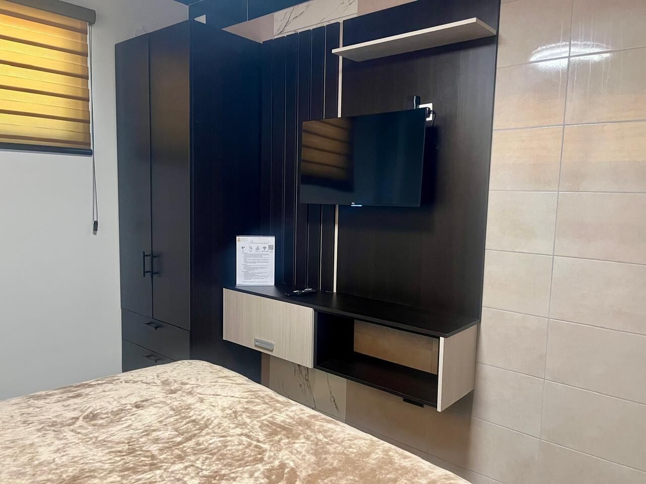 Une chambre à coucher comprenant un lit, une armoire intégrée et un téléviseur fixé au mur.