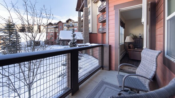 A balcony with a view of neighboring buildings and bare trees, a chair, and a lamp. - Luxury 1-bedroom ski in/ski out condo in lovely Granby Ranch (Granby)