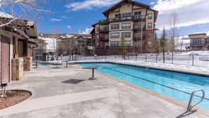 A swimming pool area with a multi-story building in the background. - Luxury 1-bedroom ski in/ski out condo in lovely Granby Ranch (Granby)