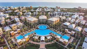 An aerial view of a resort with multiple buildings, a central pool, and a view of the ocean. - Seacrest 4BR on 30A | Walk to Dining, Shops + Beach (Inlet Beach)