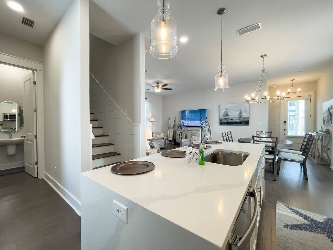 A modern kitchen with a large island, stainless steel appliances, and pendant lighting.