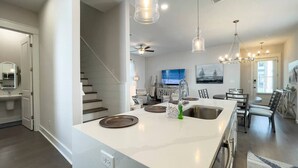 Een moderne keuken met een groot eiland, roestvrijstalen apparatuur en hangende verlichting.
