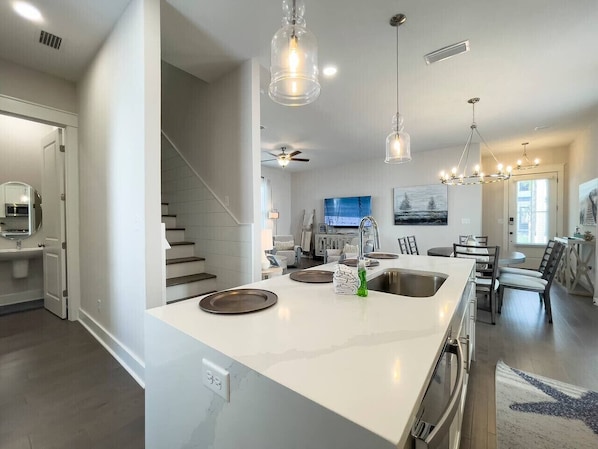 A modern kitchen with a large island, stainless steel appliances, and pendant lighting.