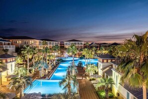 Ein Resort mit einem zentralen Schwimmbad, mehreren Gästevillen und Palmen.