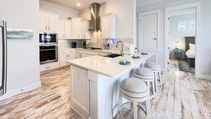 A modern kitchen with white cabinetry, a central island with bar stools, and a large island with a sink.