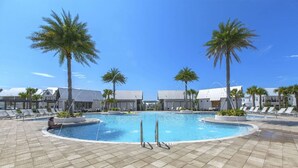 A pool area with lounge chairs and palm trees, surrounded by buildings with a modern design.