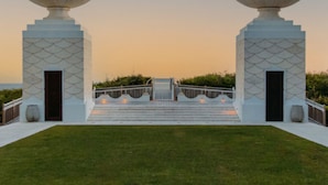 A symmetrical outdoor structure with two large, white, dome-shaped elements on either side, a central staircase, and a clear sky.