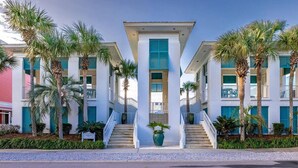 Un hotel con una escalera central, varios pisos y palmeras.