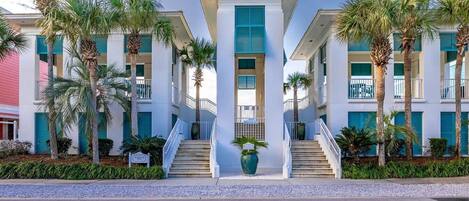 Un hotel con una escalera central, varios pisos y palmeras.