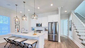 A modern kitchen with a central island, stainless steel appliances, and a staircase leading to another level.