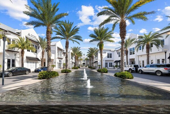 A street lined with palm trees and a central water feature.