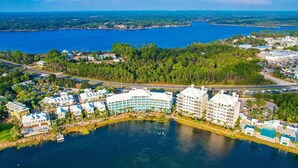 Vista aérea de un complejo turístico costero con varios edificios de hotel, un puerto deportivo y una extensa superficie de agua.