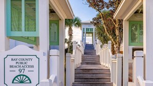 Una escalera de madera que lleva a un edificio con contraventanas verdes, con la inscripción "Bay County Public Beach Access 97".