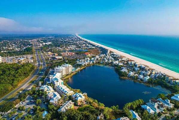 Vista aérea de un pueblo costero con playa, puerto deportivo y edificios residenciales.