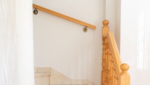 Una escalera con escalones de mármol y balaustres de madera, que conduce a un rellano con barandilla de madera.